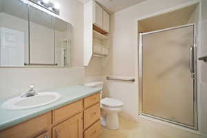 Bathroom featuring vanity, tile walls, toilet, a shower stall, and tile patterned floors