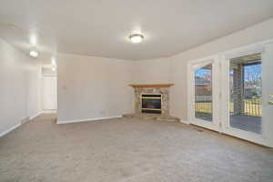 Unfurnished living room featuring baseboards, a fireplace, visible vents, and carpet