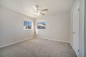 Empty room featuring baseboards, ceiling fan, and carpet