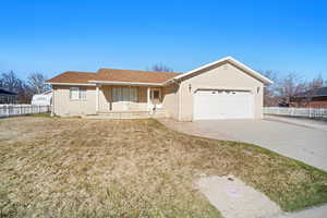 Ranch-style house featuring concrete driveway, an attached garage, fence, brick siding, and a front lawn