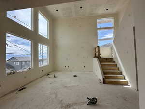 Unfurnished living room featuring stairway and a healthy amount of sunlight