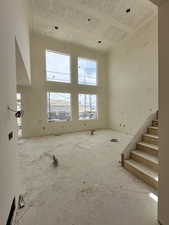 Unfurnished living room with a high ceiling and stairs
