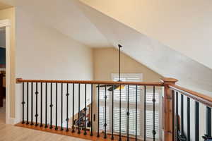 Hallway featuring wood finished floors and vaulted ceiling