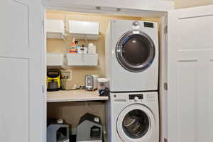 Clothes washing area featuring stacked washer and dryer and laundry area