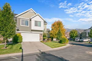 View of front of home featuring stone siding, driveway, a mountain view, a front lawn, and a garage