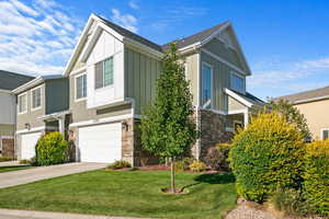 View of front of house featuring stone siding, a garage, and board and batten siding