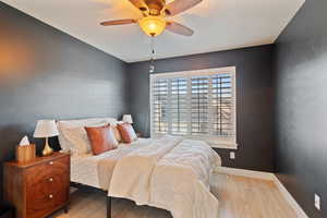 Bedroom with baseboards, wood finished floors, and a ceiling fan