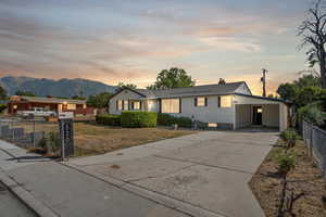 Single story home featuring fence, driveway, a mountain view, a carport, and a chimney