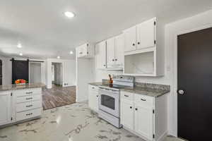 Kitchen featuring marble finish floor, white cabinetry, under cabinet range hood, and white electric range