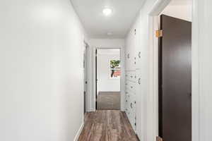 Corridor with dark wood-type flooring and baseboards