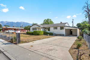 Ranch-style home with concrete driveway, a chimney, fence, a carport, and a mountain view