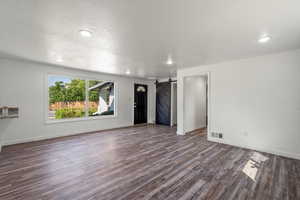 Interior space featuring a barn door, a textured ceiling, visible vents, and wood finished floors