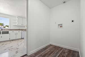 Clothes washing area with a textured ceiling, electric dryer hookup, laundry area, baseboards, and hookup for a washing machine