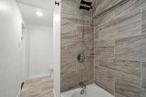 Bathroom with baseboards, toilet, and shower / bathing tub combination