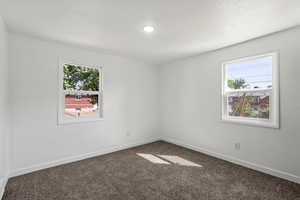 Spare room featuring baseboards, carpet floors, and a textured ceiling