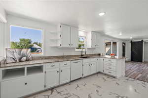 Kitchen with a sink, white cabinetry, a peninsula, white dishwasher, and marble finish floor