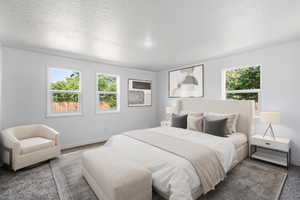 Bedroom with multiple windows, baseboards, carpet flooring, and a textured ceiling