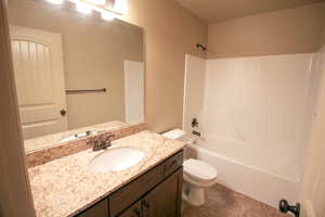 Bathroom featuring  shower combination, vanity, and dark tile patterned flooring