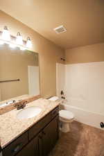 Bathroom featuring shower / washtub combination, vanity, and dark tile patterned floors