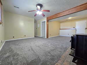 Unfurnished living room featuring ceiling fan, carpet floors, baseboards, and a textured ceiling