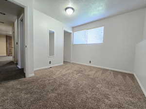 Unfurnished bedroom featuring carpet floors, baseboards, and a textured ceiling