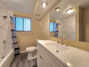 Full bathroom featuring vanity, plenty of natural light, toilet, and baseboards