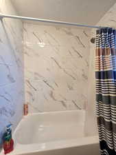 Bathroom with shower / tub combo with curtain and a textured ceiling