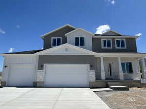 View of front of house featuring an attached garage, stone siding, board and batten siding, a porch, and driveway
