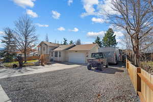 View of front of house with concrete driveway, a garage, and fence