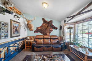 Carpeted living area with vaulted ceiling and wainscoting