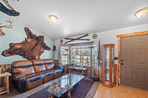 Living area featuring vaulted ceiling, wood finished floors, and a textured ceiling