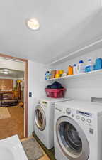 Clothes washing area with washing machine and dryer, a textured ceiling, and laundry area