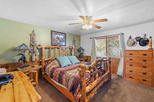 Master Bedroom featuring carpet, a textured ceiling, wooden walls, a ceiling fan, and wainscoting