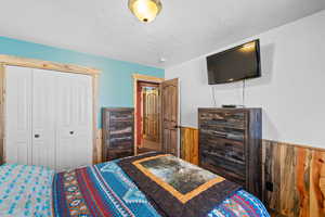 Bedroom featuring a wainscoted wall, a closet, and wooden walls