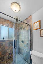 Bathroom featuring a shower stall, toilet, and a textured ceiling