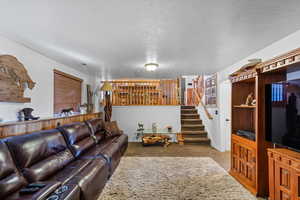 Carpeted living room featuring visible vents, stairway, and a textured ceiling