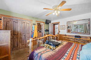 Master Carpeted bedroom with a ceiling fan, a wainscoted wall, and a textured ceiling