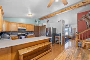 Kitchen with light countertops, lofted ceiling with beams, under cabinet range hood, a sink, and appliances with stainless steel finishes