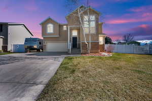 Traditional-style home featuring stucco siding, fence, driveway, a garage, and a yard