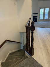 Stairs with a tiled fireplace, baseboards, and wood-type flooring