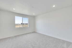 Empty room with baseboards, recessed lighting, and light carpet
