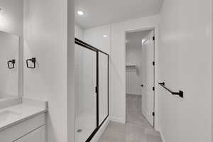 Full bathroom with baseboards, recessed lighting, a shower stall, vanity, and a walk in closet