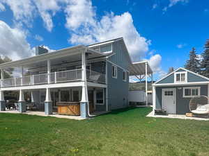 Rear view of property with a hot tub, a balcony, a chimney, board and batten siding, and a patio