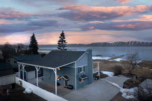 Exterior space with a water and mountain view, board and batten siding, fence, and roof with shingles