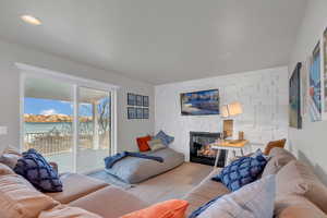 Carpeted living area with a stone fireplace, a water view, and recessed lighting