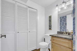 Bathroom featuring a closet, toilet, and vanity