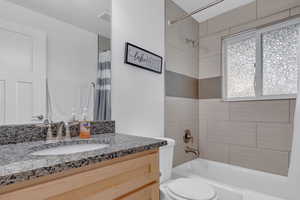 Full bathroom with shower / bath combo, visible vents, toilet, and vanity