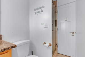 Bathroom featuring an enclosed shower, toilet, and vanity