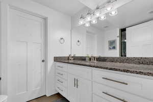 Bathroom featuring toilet, visible vents, wood finished floors, and vanity