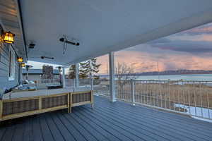 Deck with an outdoor living space, a water view, and a beach view